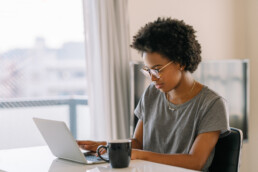 Young black beautiful woman using laptop at home