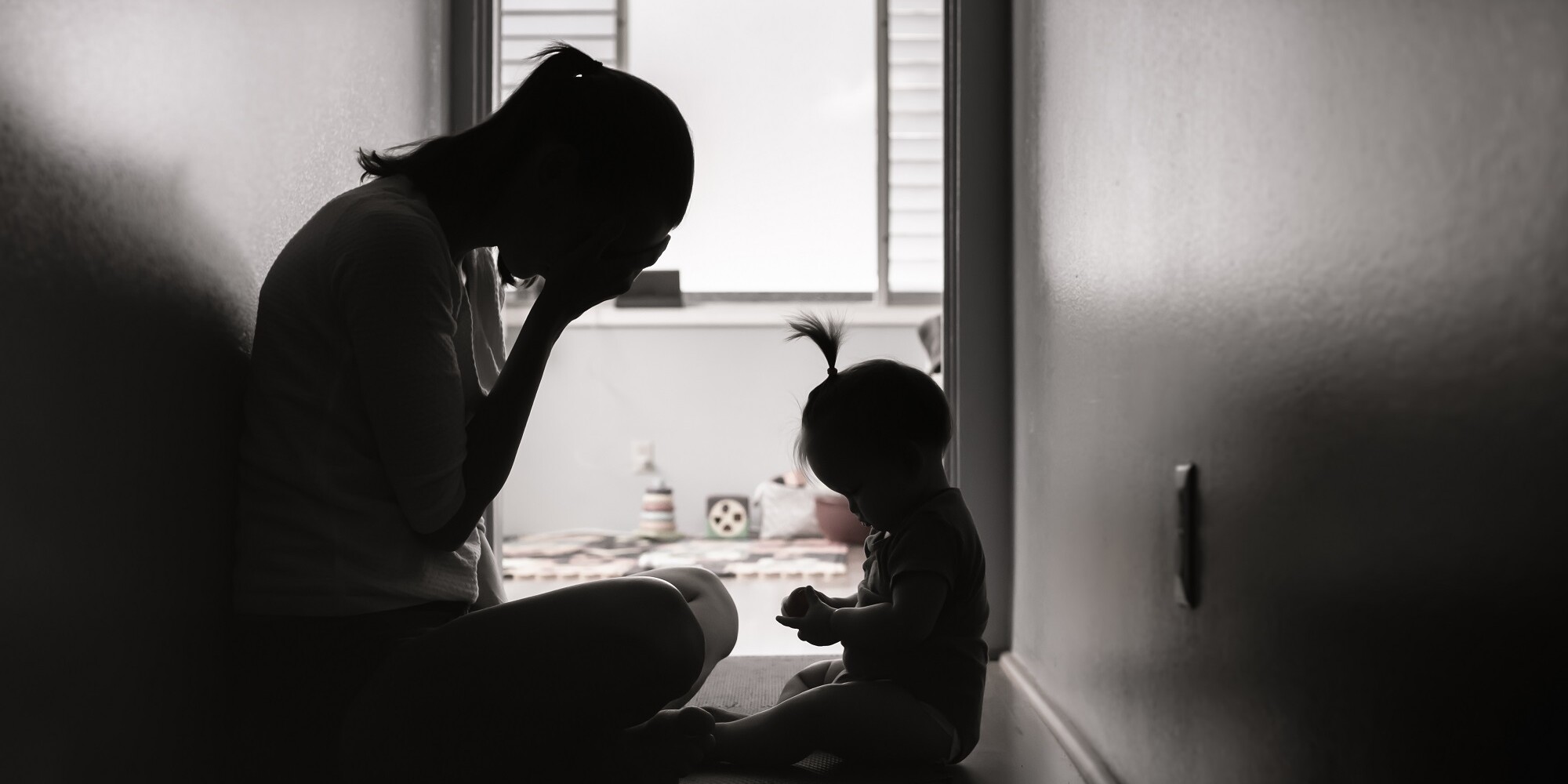 Stressed and tired mother sitting on the floor with her baby girl.